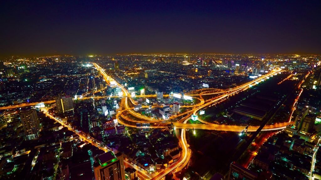Stunning aerial view of Bangkok's illuminated skyline and busy highways at night.