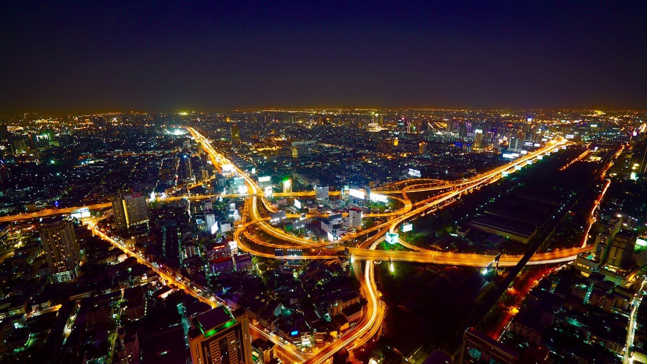 Stunning aerial view of Bangkok's illuminated skyline and busy highways at night.