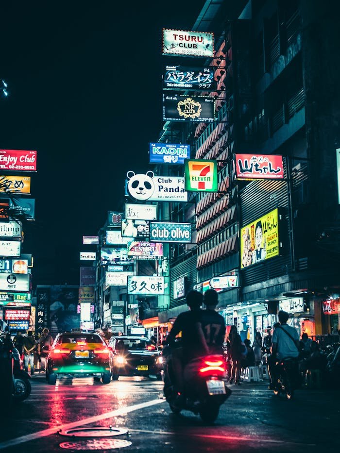 Experience the lively urban atmosphere of Bangkok's downtown nightlife filled with bright signs and bustling streets.